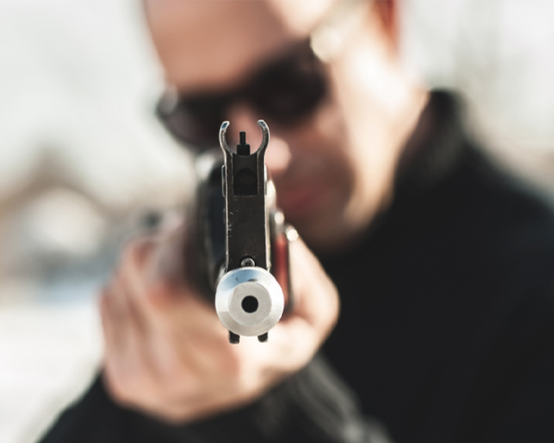 一名持槍者正面朝向畫面，象徵頭部中槍的夢境。