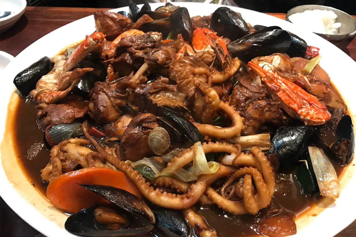 韓國燉雞及海鮮的驚艷搭配，盤中有肉質嫩滑的雞肉和多樣海鮮。