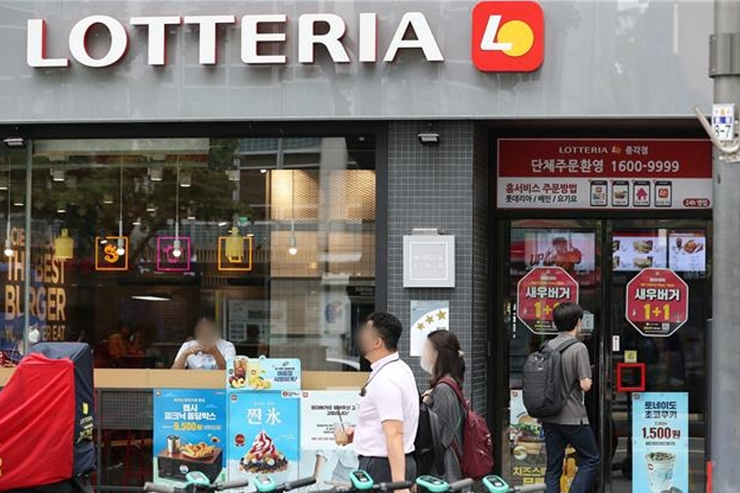 Lotteria快餐店的外觀，門口有行人經過，反映疫情期間的營業模式。