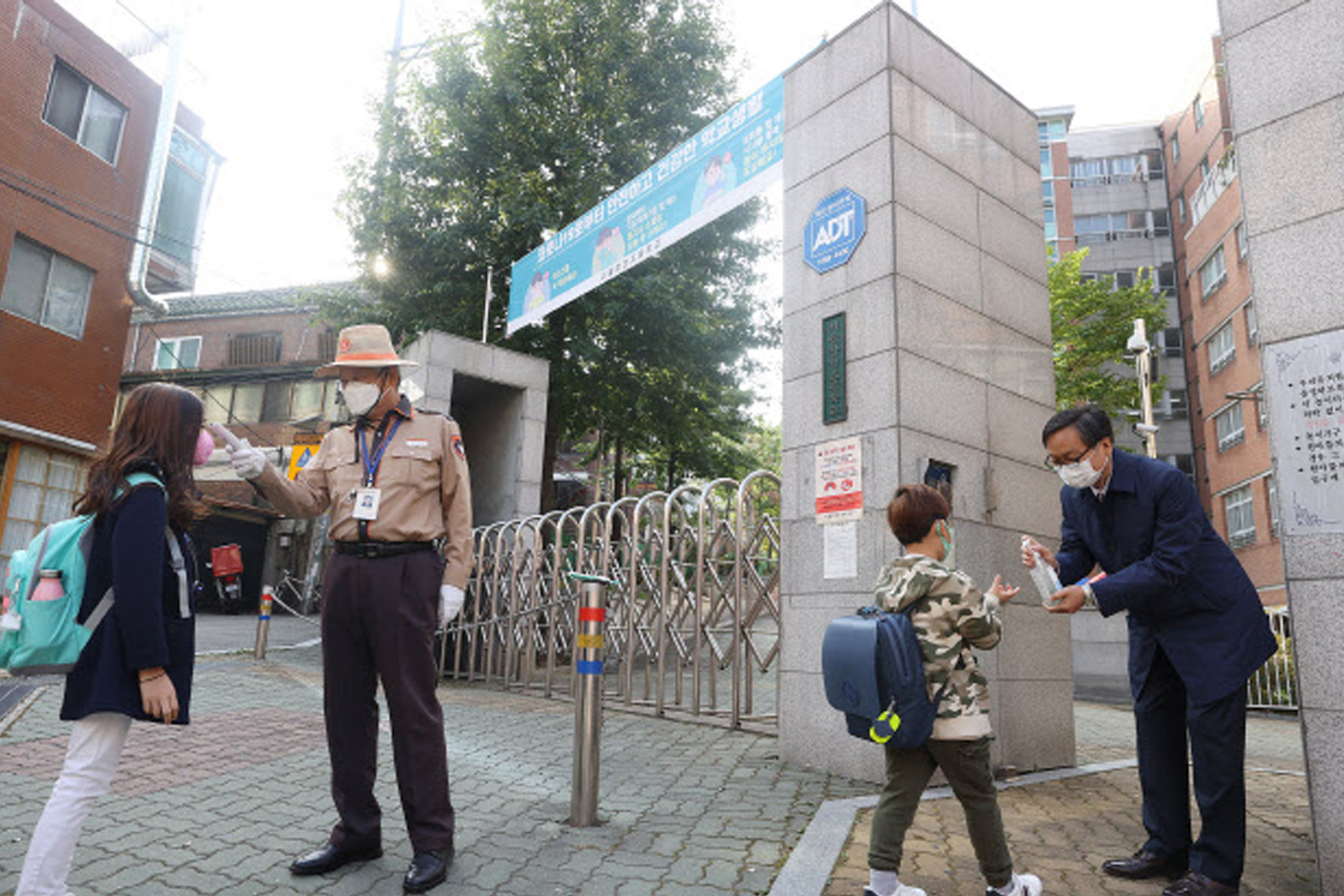 在學校入口，保安進行體温檢測，以保障校園安全，所有人皆戴口罩。