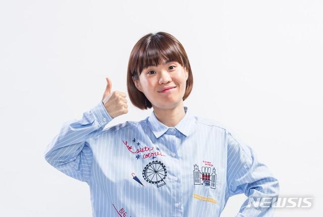 青いシャツを着たパク・ジソンが親指を立ててポーズを取る姿。背景には白いスタジオが見える。