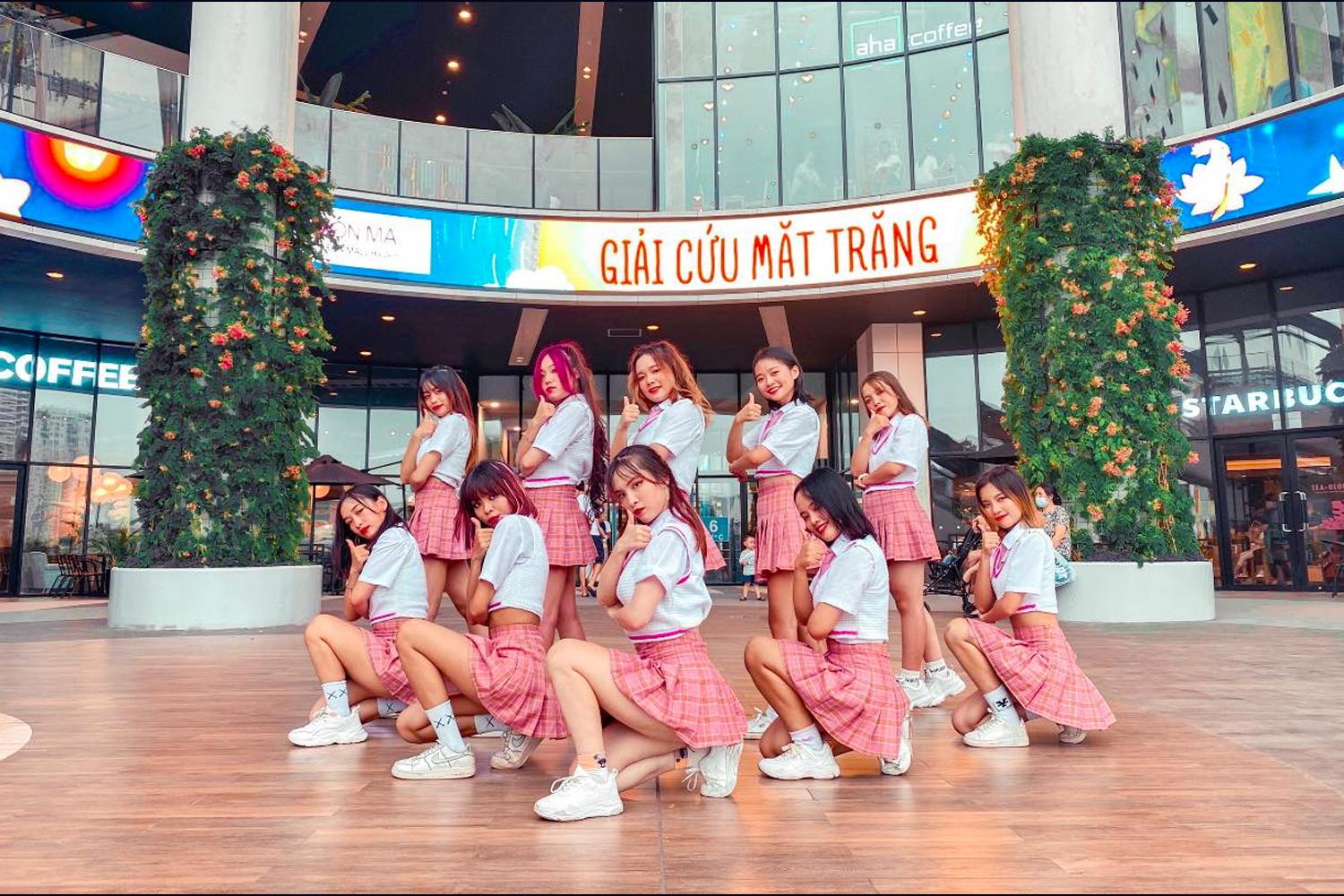 Các thành viên nhóm nhảy FGDance mặc trang phục trắng sắp xếp đội hình biểu diễn dưới trời xanh trên phố đông đúc.