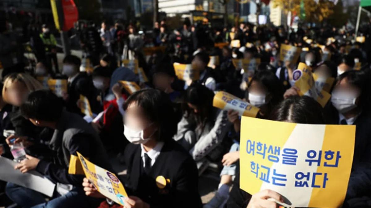 การชุมนุมเพื่อสิทธินักเรียนหญิงในโซล, กลุ่มนักเรียนหญิงเกาหลีใต้ถือป้ายเรียกร้องความเสมอภาคทางเพศในโรงเรียน บางคนสวมหน้ากากอนามัย ณ การชุมนุมประท้วง ใกล้บริเวณสถานที่ในเขตเมืองที่มีอาคารสูงเรียงราย