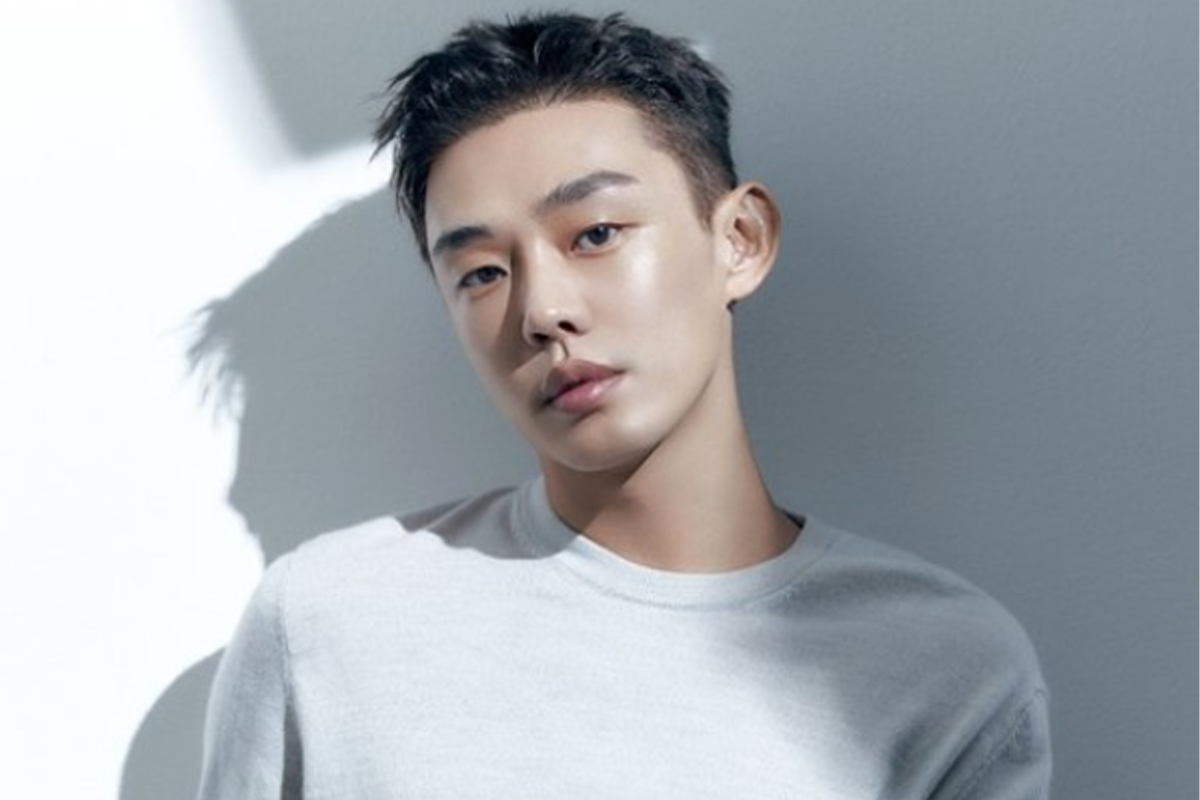 劉亞仁清新白色毛衣，輕盈站立在背景中黑白對比的牆前，光影的自然變化增加了他的神秘感。