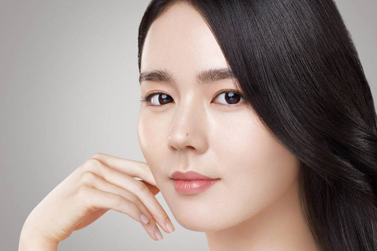 韓佳人以清新的姿態靠在手腕上，展現出她温柔的氣質。一頭烏黑秀髮搭配柔和的燈光，背景為簡單的白牆，突顯出她的端莊大方。