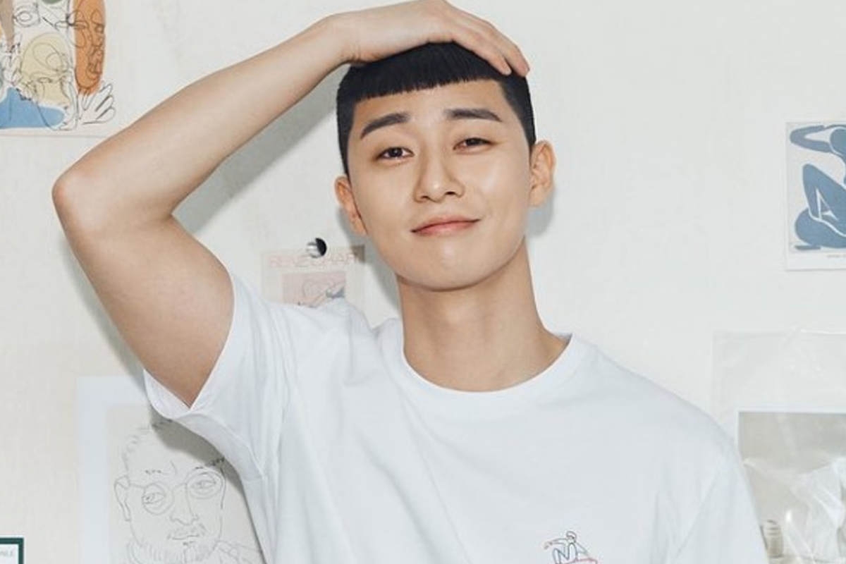 樸敍俊穿着白色T恤，一手隨意放在頭上，背景貼着藝術畫，展現出他的隨性與魅力。