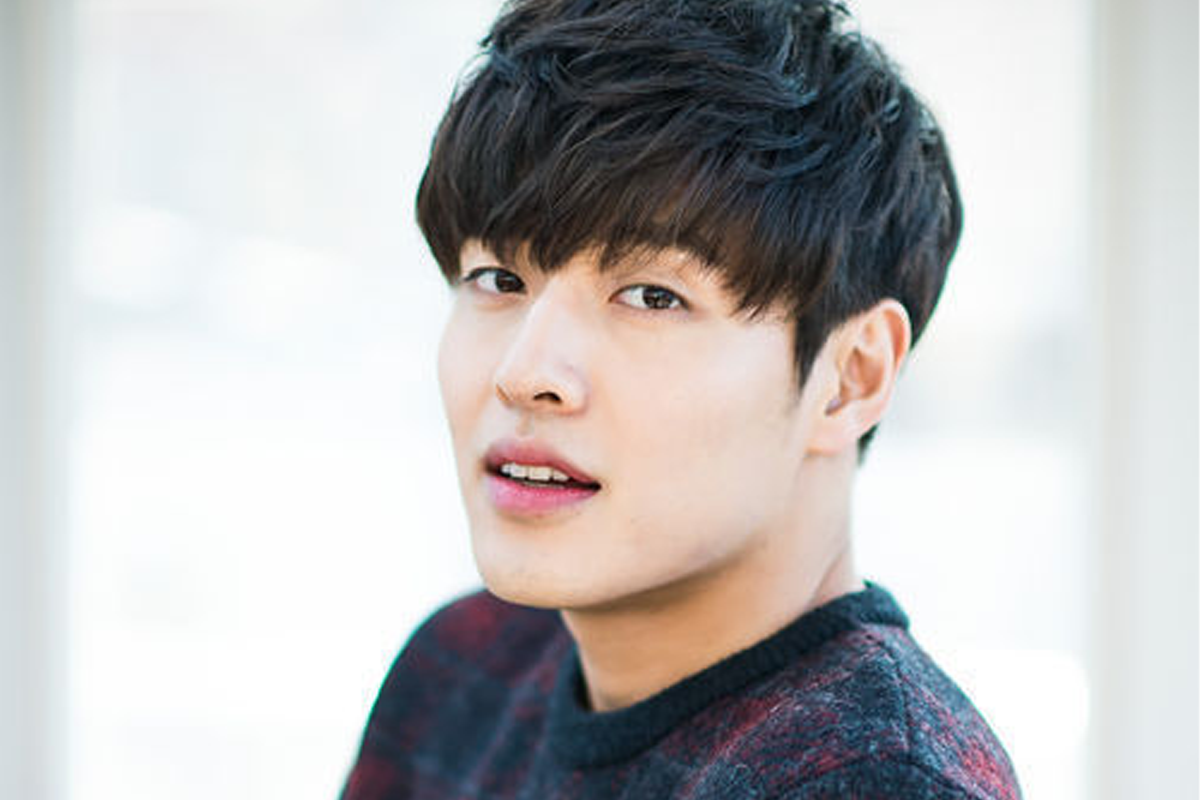 姜河那身穿白色襯衫，搭配淡雅的背景，坐在柔軟沙發上，給人一種舒適放鬆的感覺。