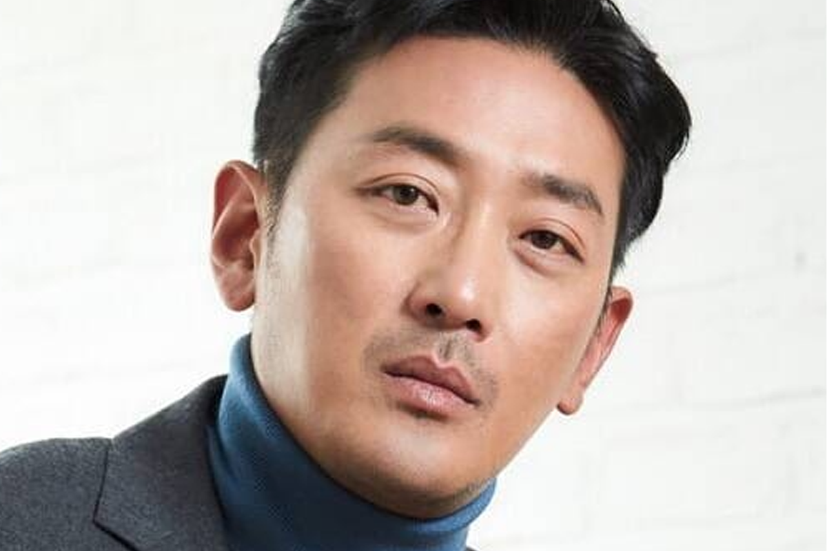 河正宇身着深色高領毛衣，特寫鏡頭下突出其成熟穩重的氣息，背景為乾淨簡單的白牆，增添了視覺效果。