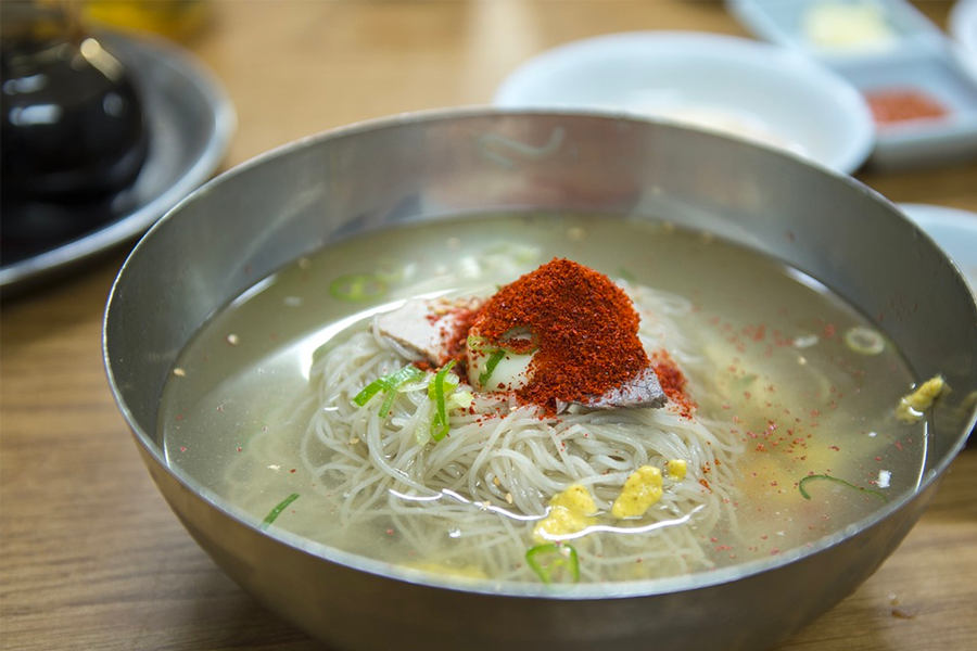傳統的韓國冷麵，在碗中服務，與蕎麥麵條和辛辣的辣椒調料混合，展現古老的韓國文化。