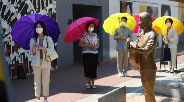 การปฏิบัติป้องกัน COVID-19 ด้วยการใช้ร่มสีสันสดใสคั่นระยะห่างในที่สาธารณะในเกาหลีใต้