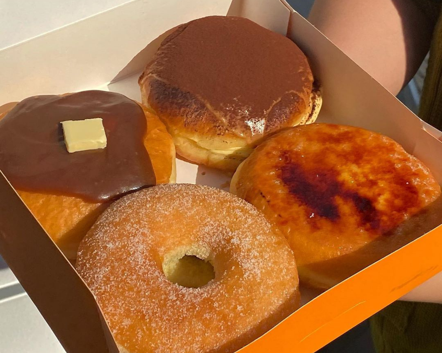 서울 강남에 위치한 피르마(Pyrma)의 다채로운 도넛 박스, 초콜릿, 티라미수, 카라멜 브룰레가 포함된 도넛 컬렉션, 다양한 맛의 한국 도넛