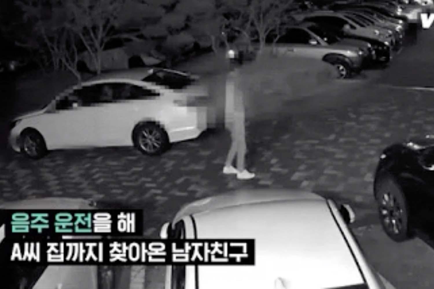 ภาพจากกล้องวงจรปิดในที่จอดรถแสดงเหตุการณ์ที่คนเดินเข้าใกล้รถสีขาว มีข้อความภาษาเกาหลีที่ปรากฏด้านบนของภาพ.