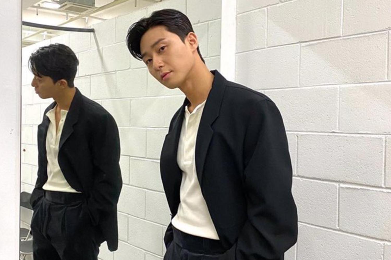 韓國演員樸敍俊在鏡子前擺姿勢，身穿黑色西裝外套和卡其色褲子。