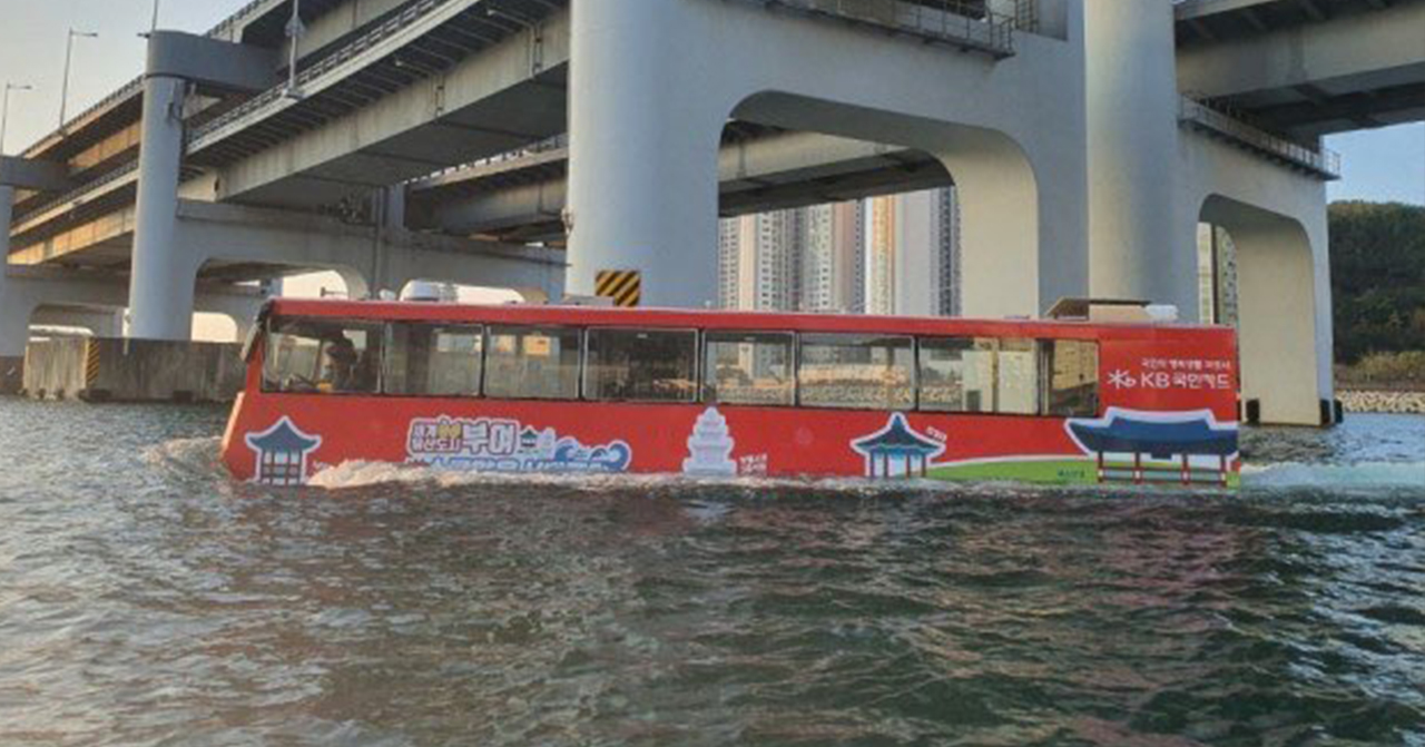 韓國海陸兩用巴士在水中行駛，背景顯示橋樑