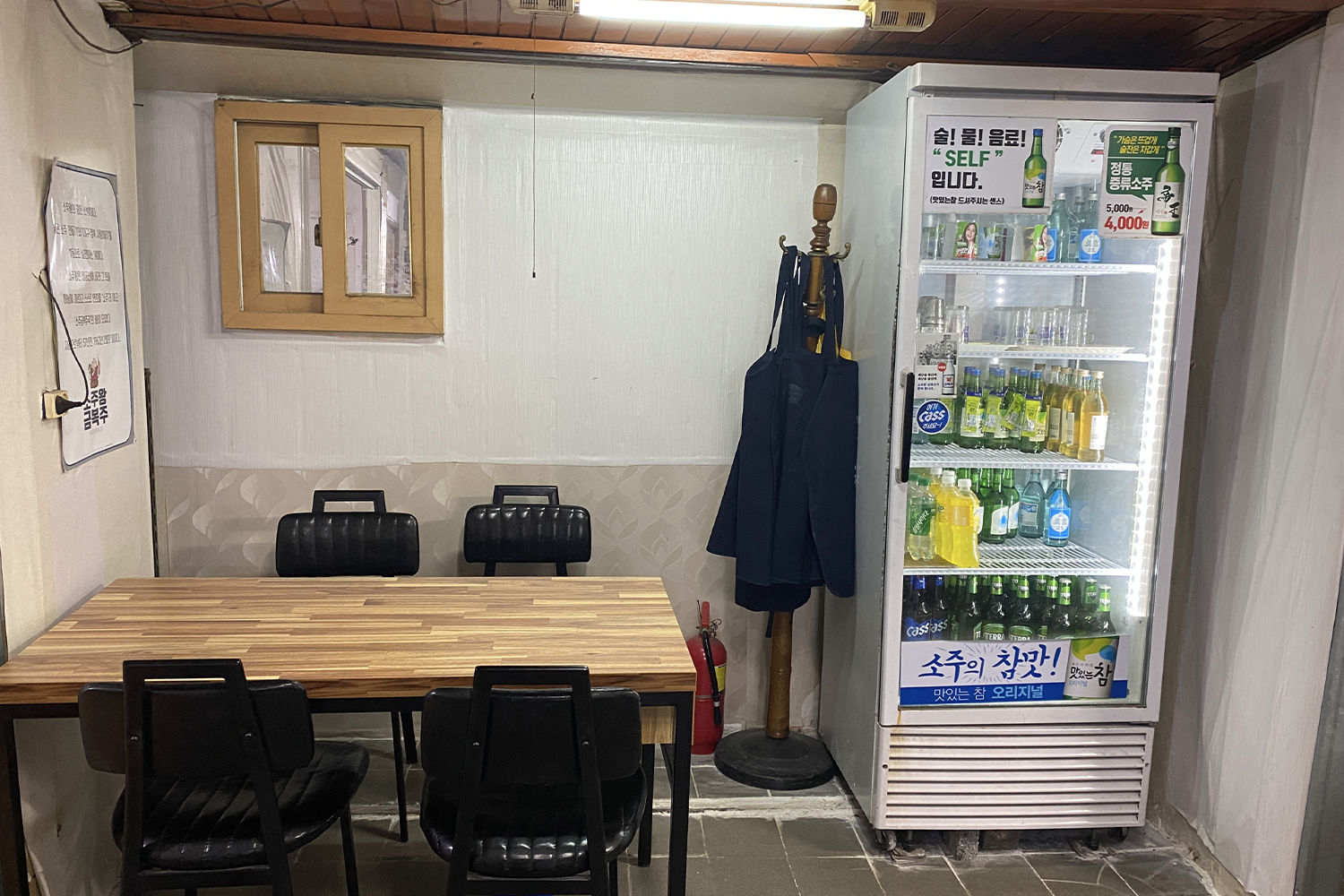 a wooden table, 4 black chairs and a liquor fridge, a typical appearance of a restaurant in korea, at wanggeomi sikdang in daegu, south korea