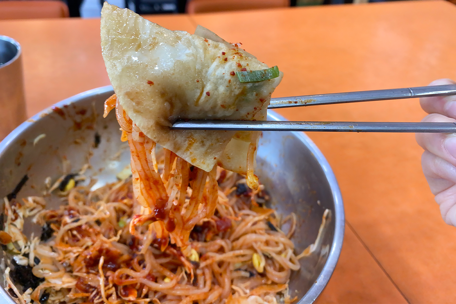 taking a chopstick full of korean cold noodles jjolmyeon