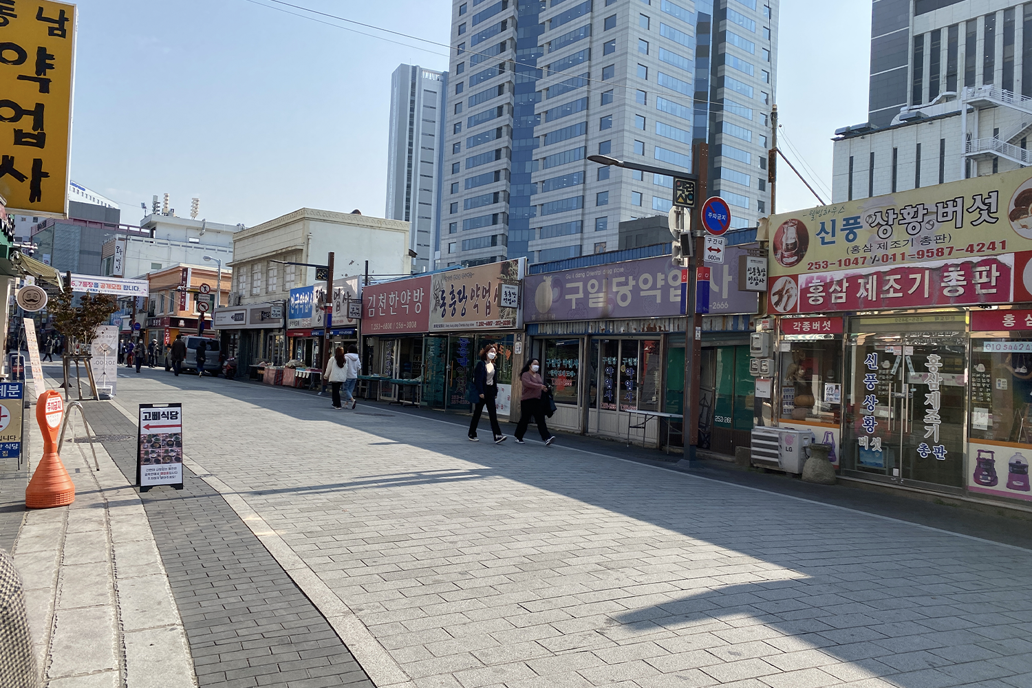 大邱药令市街景,韩国传统市场药材店铺,周围高楼林立。