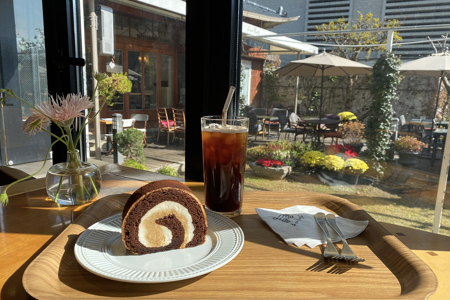 LAMIA EMILY咖啡馆内的蛋糕与咖啡,窗外可见庭院景色。