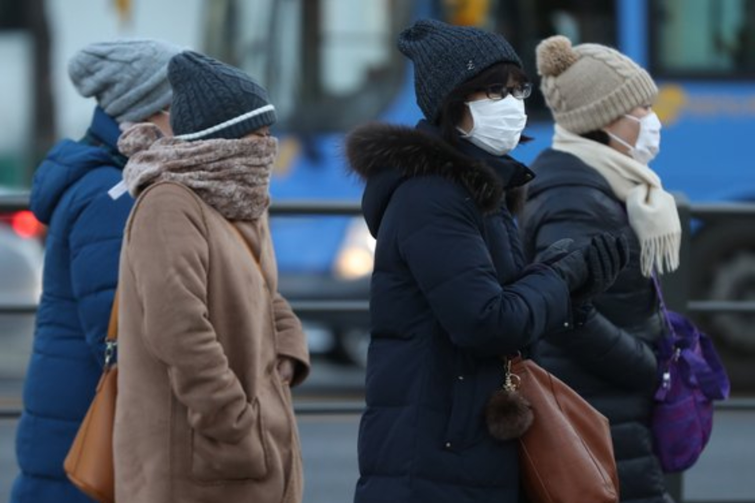 三位穿著厚重冬季衣物的韓國人在寒冷的街道上走著，展現韓國冬季的嚴寒與冬季服裝的搭配。