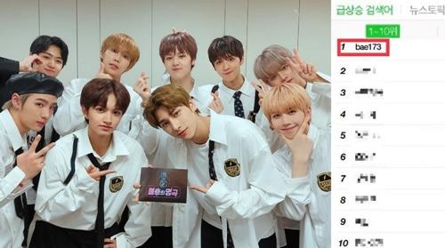 韓国のアイドルグループBAE173が白い衣装を着て、KBS2番組『不朽の名曲』の舞台裏でリアルタイム検索語ランキング1位の証拠を示すプレートを持っている様子。