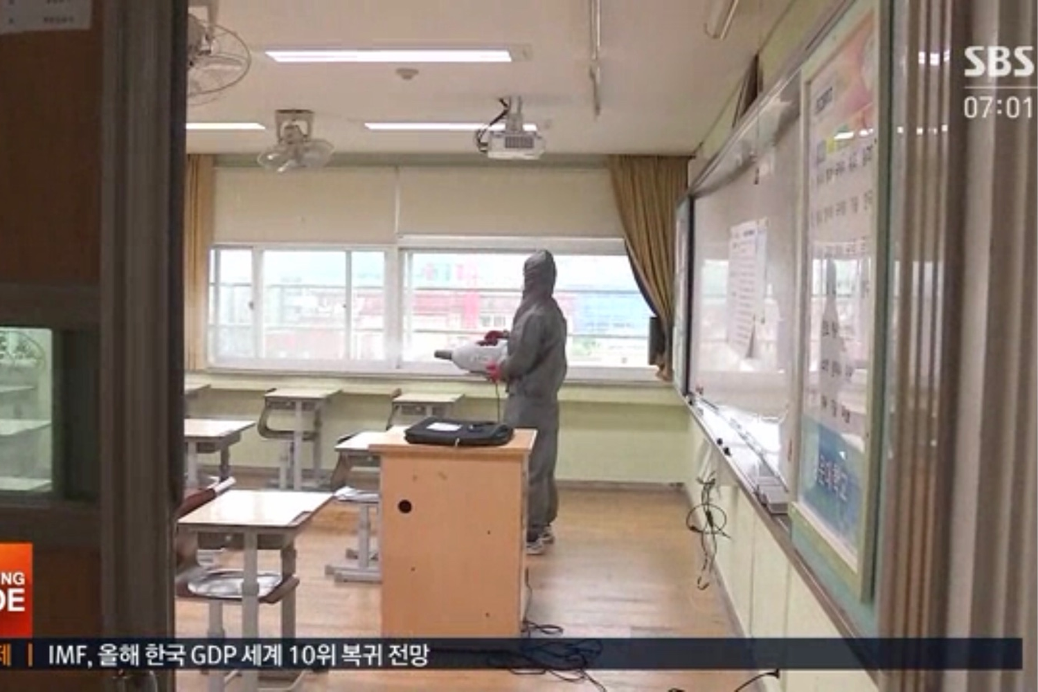 教室內一位穿著防護裝的工作人員正在使用機器進行清潔消毒，以因應COVID-19防疫措施。