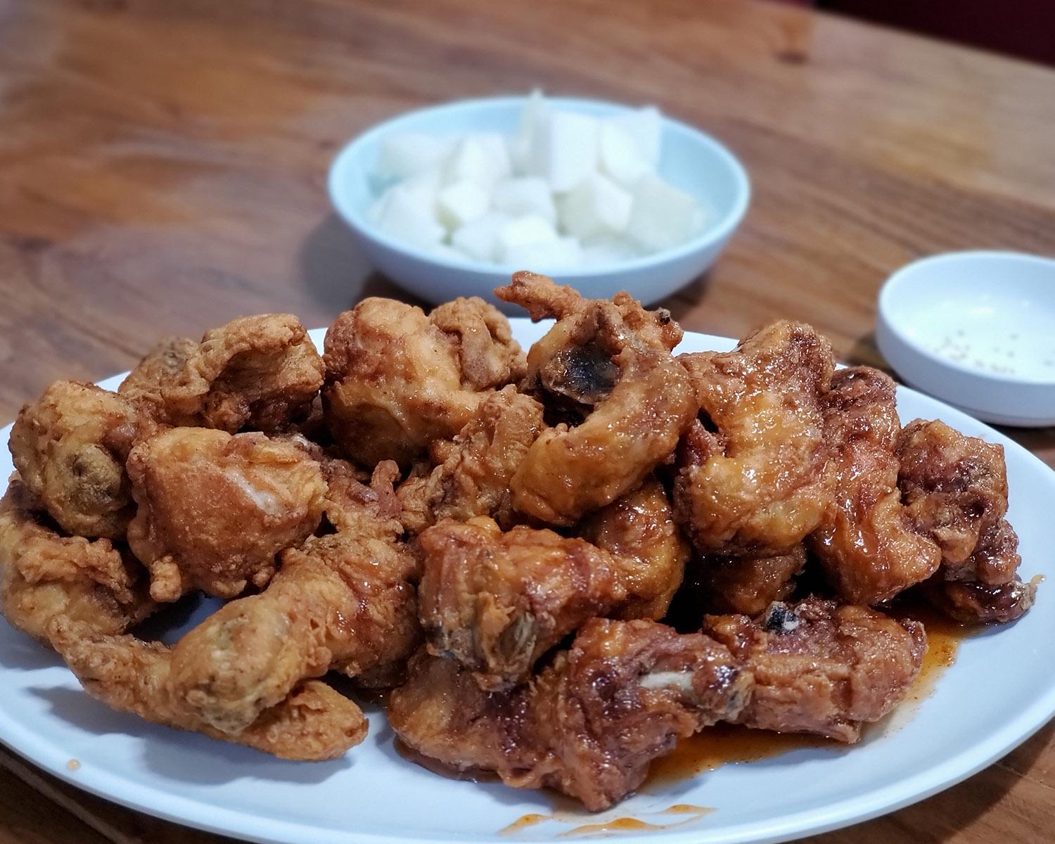 韩国原州炸鸡的特写，酥脆外皮和充满香味的酱料相得益彰。