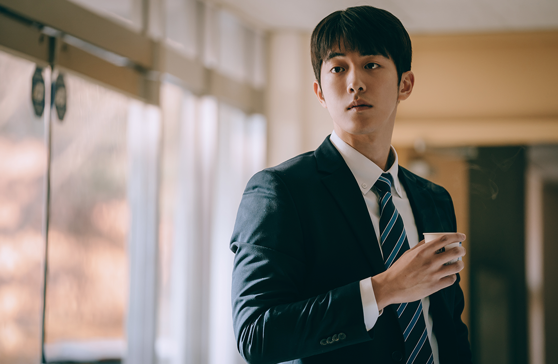 在城市街道上，女子穿著針織帽與厚外套，坐在輪椅上，旁邊是陪伴她的人。街道上的氣氛顯得非常溫馨。