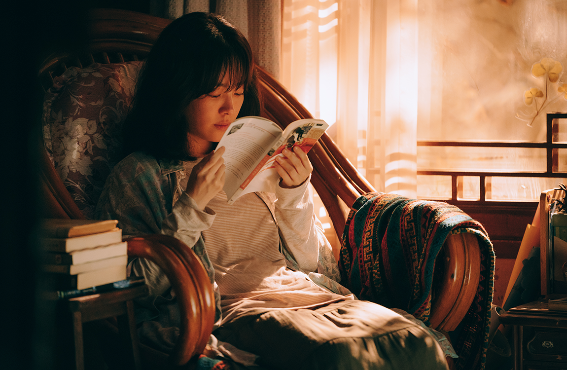 坐在老式椅子上閱讀書籍的女子，透過窗簾進入的夕陽光線讓房間顯得溫暖而寧靜。