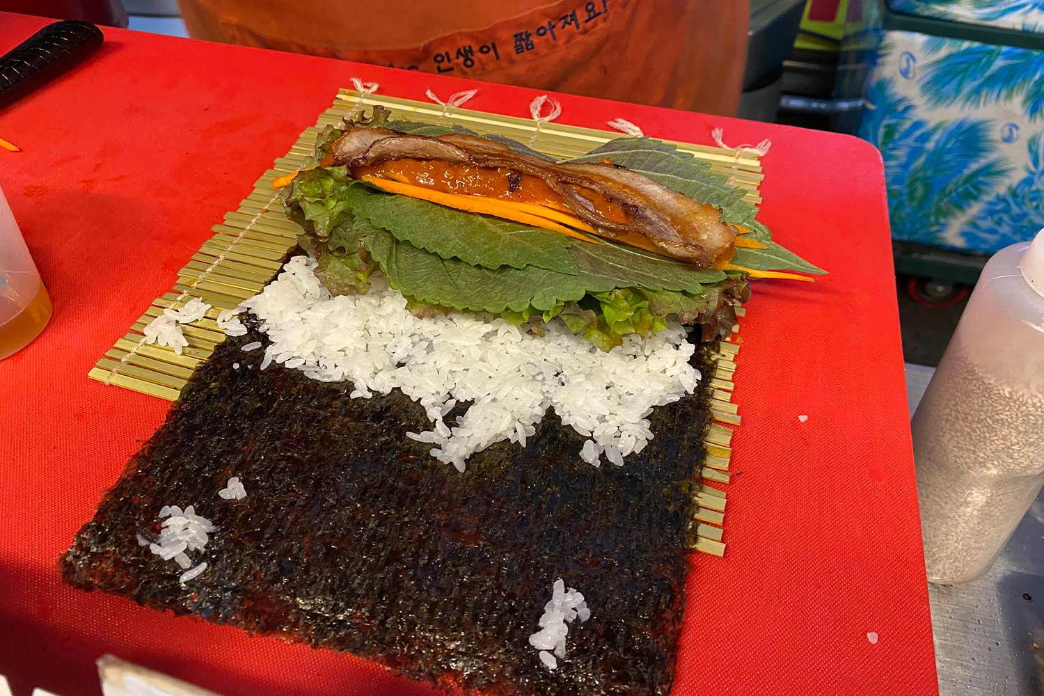 海苔とご飯の上にサムギョプサルと野菜が乗っているキムパプの準備過程