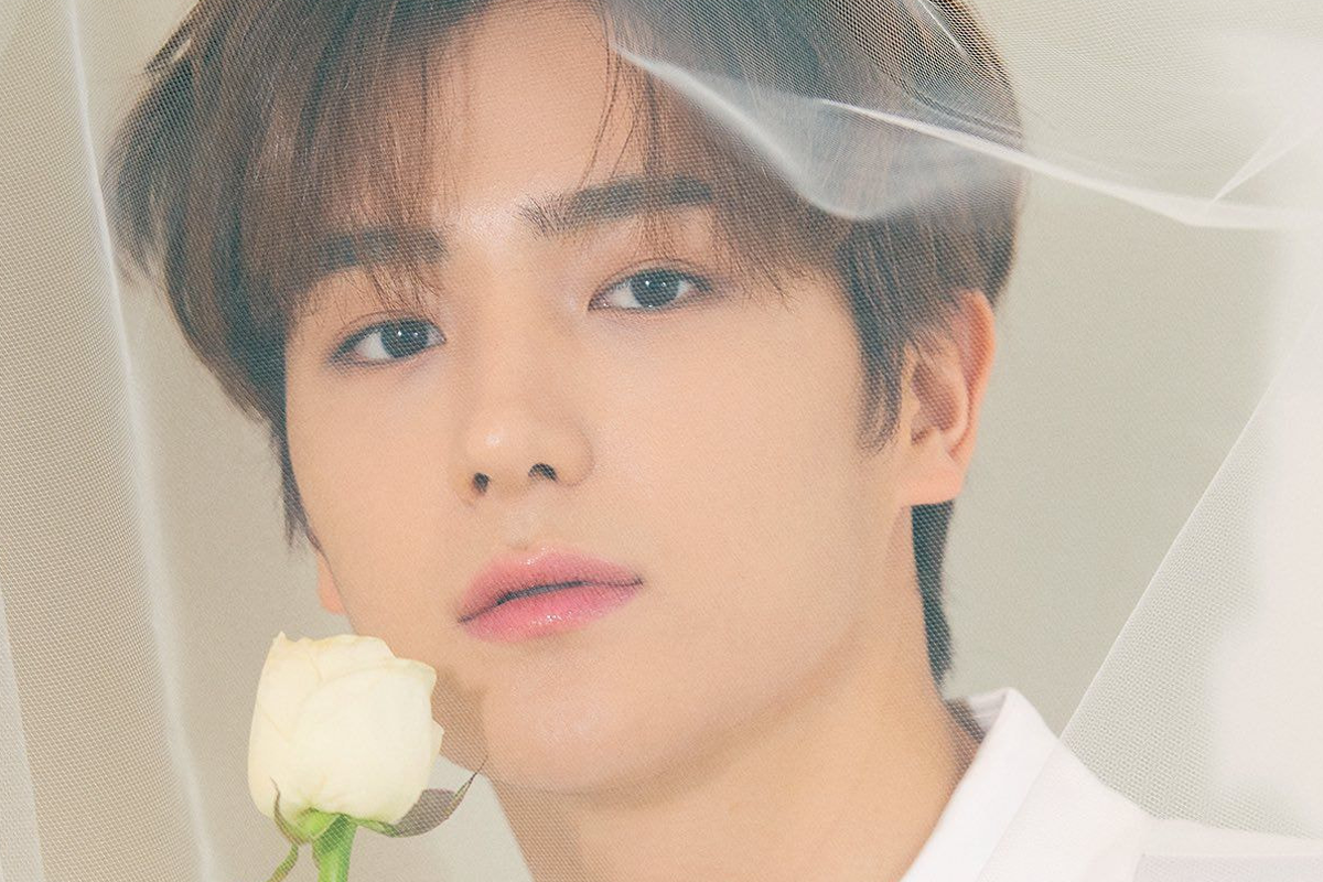 THE BOYZ成員賢在穿著黑色服裝，背景為樹幹和自然景色。