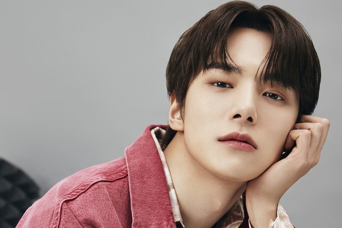 MONSTA X成員民赫於簡單背景前的姿勢，身穿紅色外套。