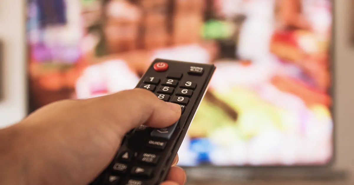 手握遙控器對著電視，強調觀看電視節目和娛樂的現代生活情境。