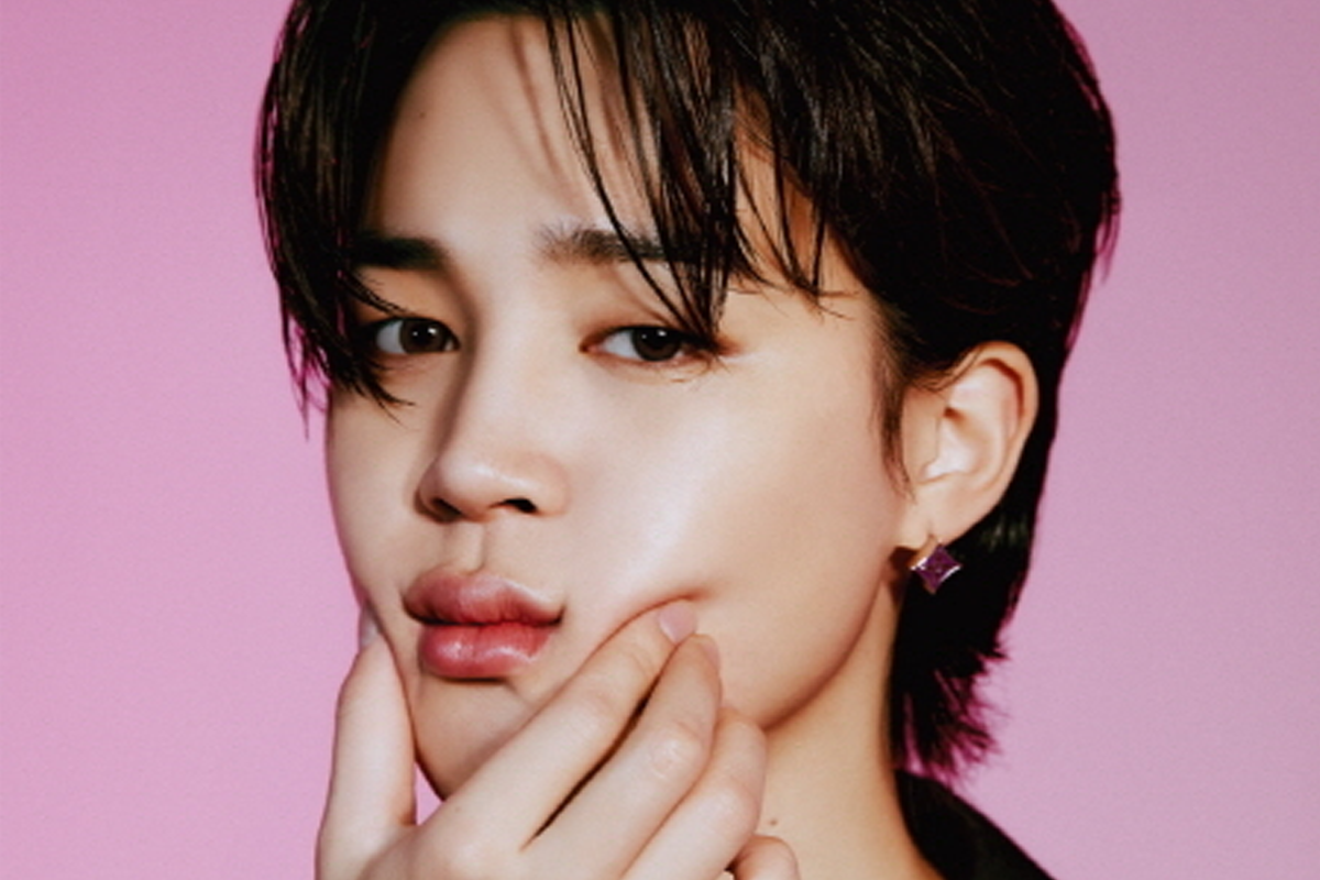 BTS成員Jimin穿著綠色外套，背後是棕色木頭背景。