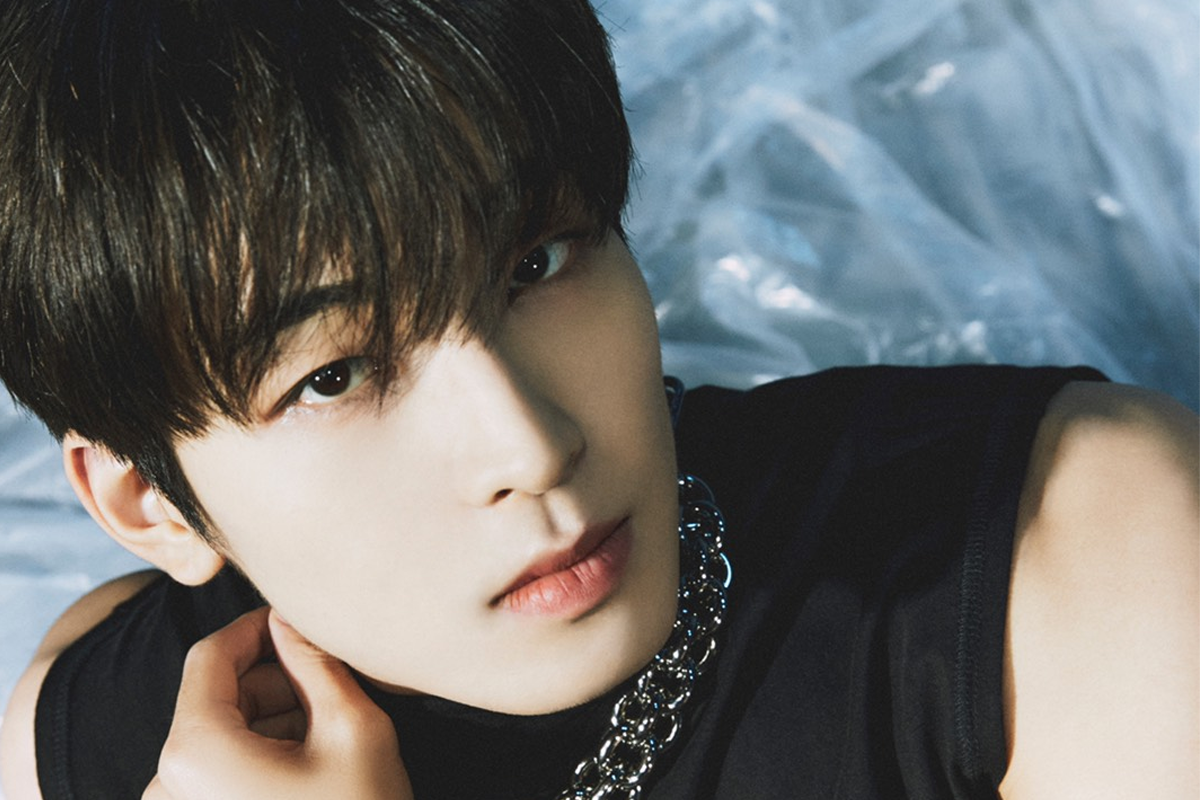 SEVENTEEN成員圓佑坐於用葉綠裝飾的背景中，身穿黑色西裝。