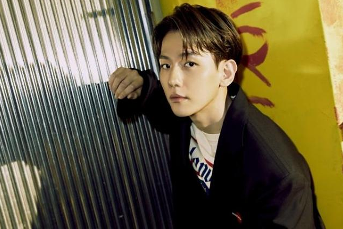 EXO成員伯賢於舞台環境身穿黑色服裝，背景為亮橙色花紋。