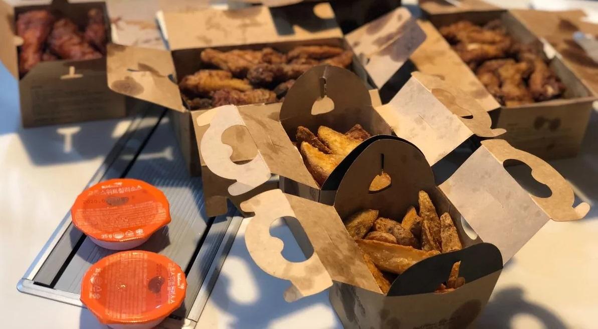 อาหารไก่ทอดหลากหลายแบบในกล่องกระดาษพร้อมซอสจุ่มสองถ้วยที่โต๊ะอาหาร