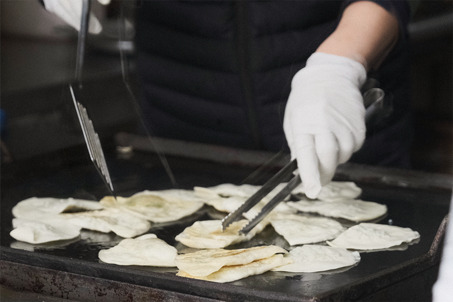 厨师在美成堂准备扁饺子的场景，使用传统的方式在铁板上煎饺子。
