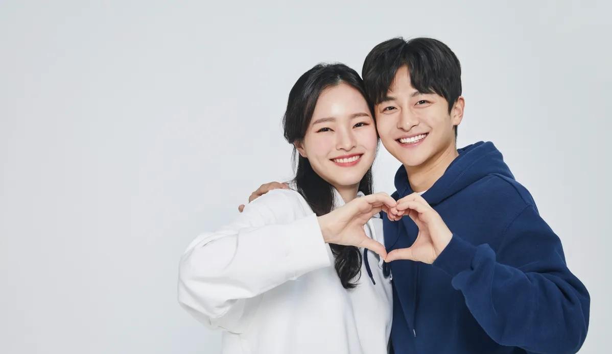 คู่รักหนุ่มสาวกำลังโพสท่าทำรูปหัวใจด้วยมือทั้งสอง เป็นภาพที่สื่อถึงความรักและความอบอุ่นในความสัมพันธ์