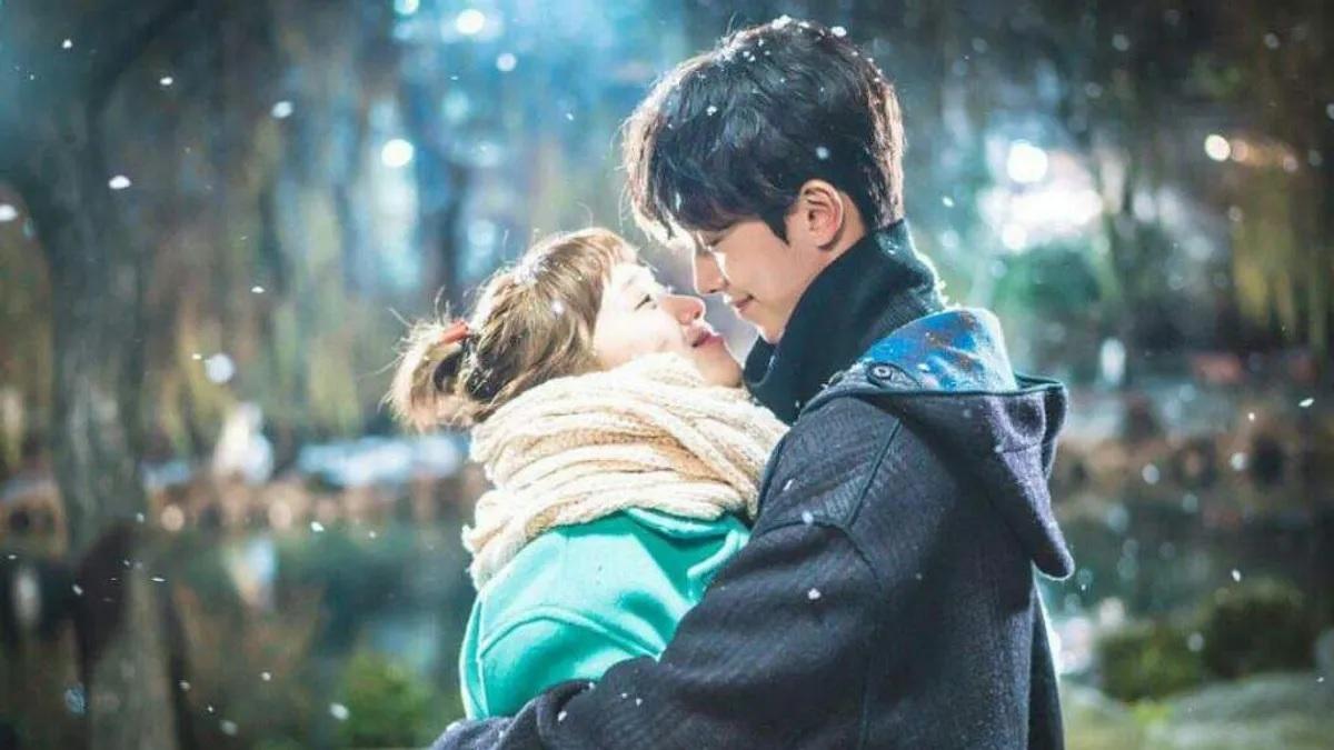 คู่รักกำลังกอดกันในบรรยากาศหนาว มีหิมะเล็กน้อยรอบๆ เป็นภาพที่สื่อถึงความรักอันอบอุ่นในฤดูหนาว