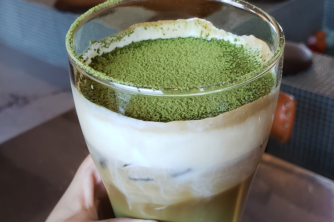 文畫裝咖啡廳的特色飲品，展示一杯蓋著厚厚奶泡的抹茶拿鐵。