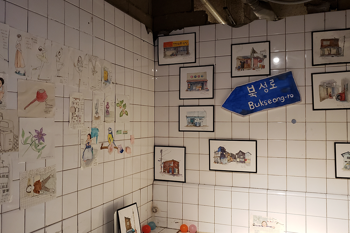 文畫裝咖啡廳浴室的牆壁上掛著一系列的水彩畫作。