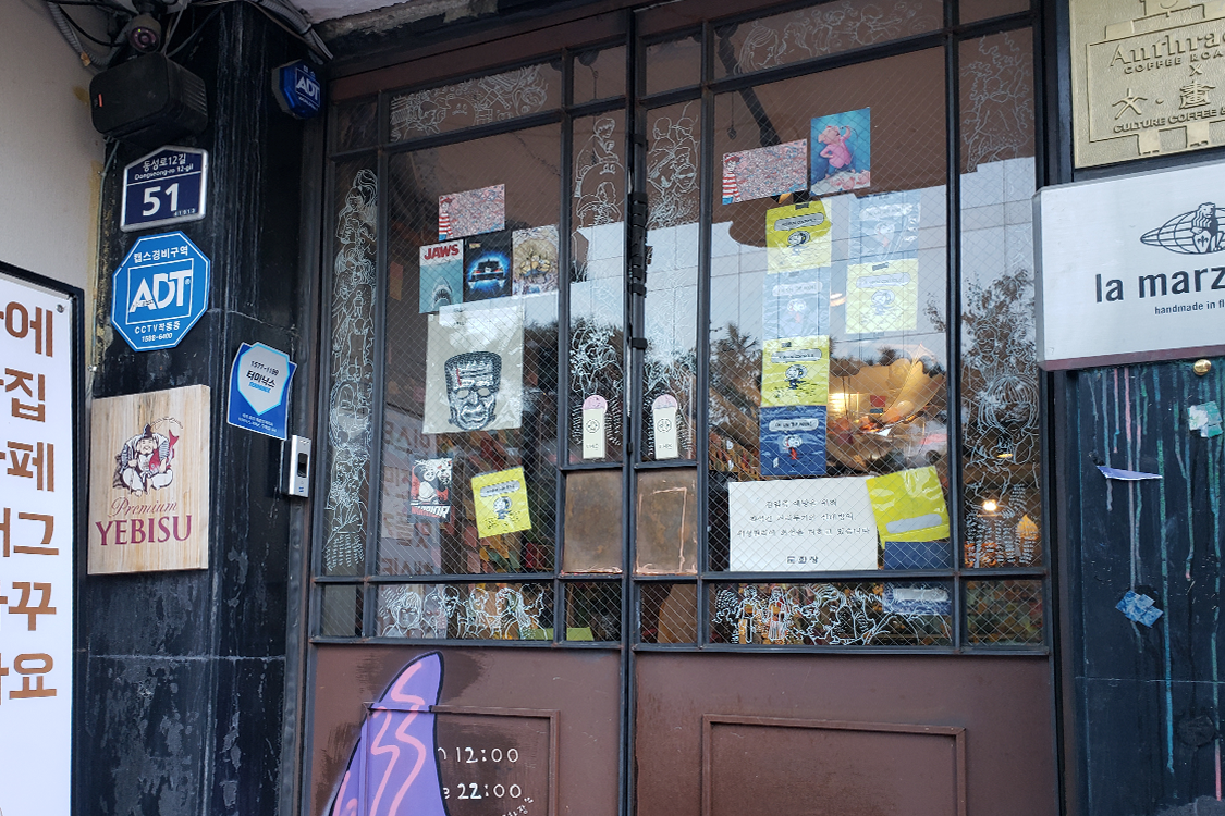 文畫裝咖啡廳入口處的玻璃大門，貼滿了貼紙和宣傳海報。