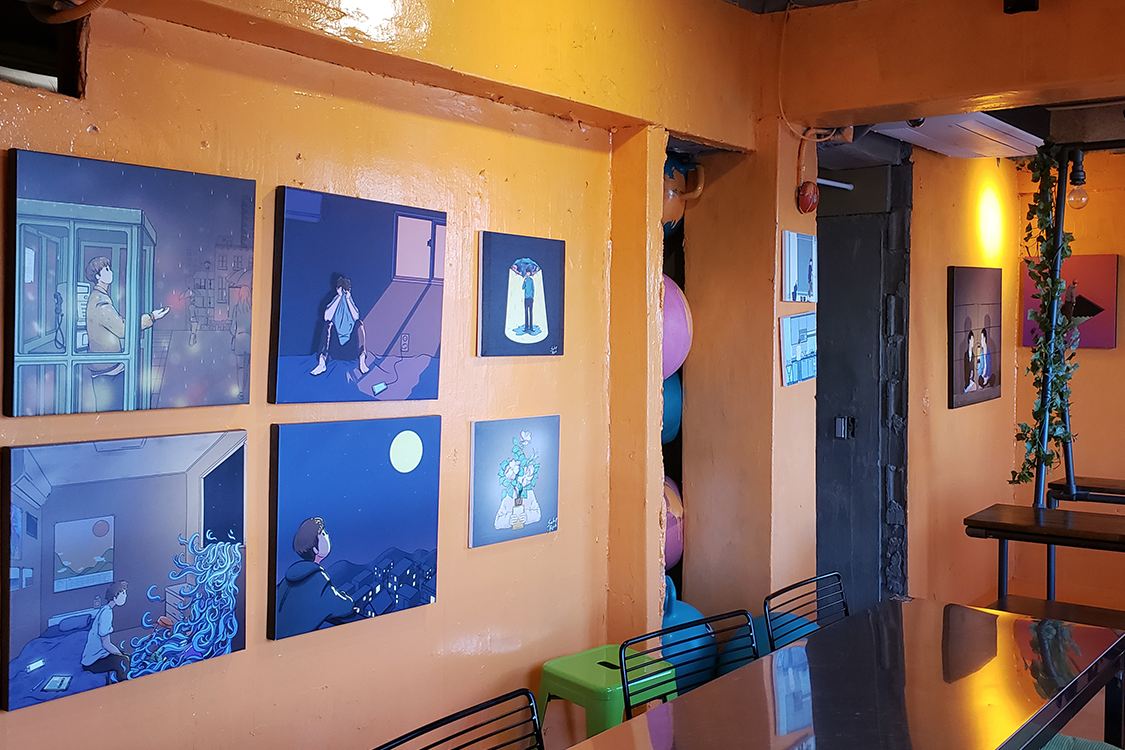 文畫裝咖啡廳的橙色牆面，掛著各式現代插畫作品。