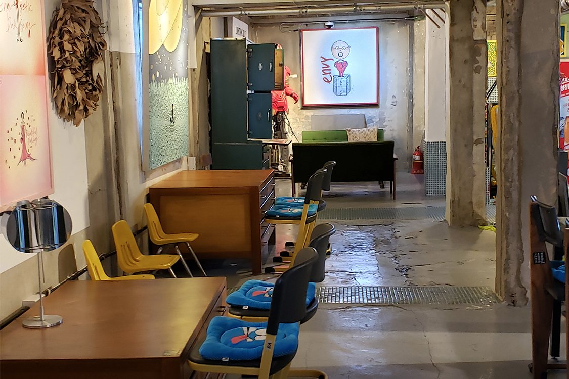 文畫裝咖啡廳的椅子與桌子，背景墻上掛著一幅藝術畫作。