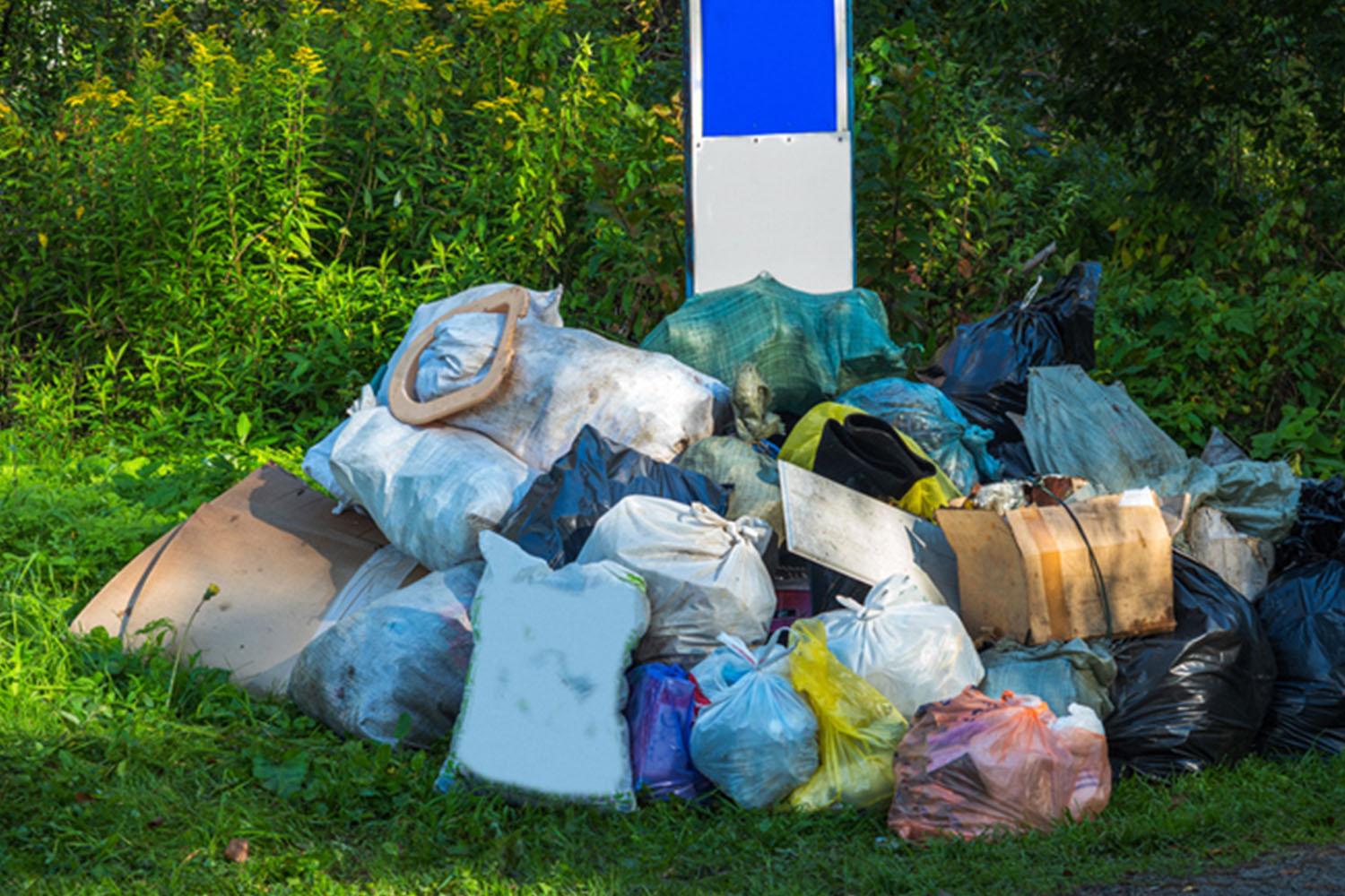 풀밭에 쌓여 있는 다양한 색상의 쓰레기 봉투들