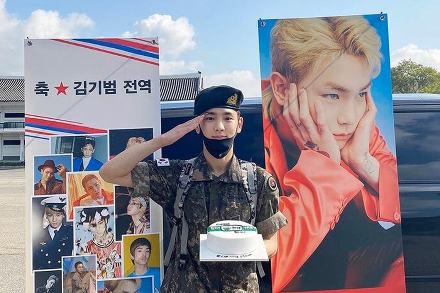 韓國軍人退伍慶祝，海報背景顯示多張合照。現場可能是在軍營或類似的場地，並有人正行舉手禮手勢。
