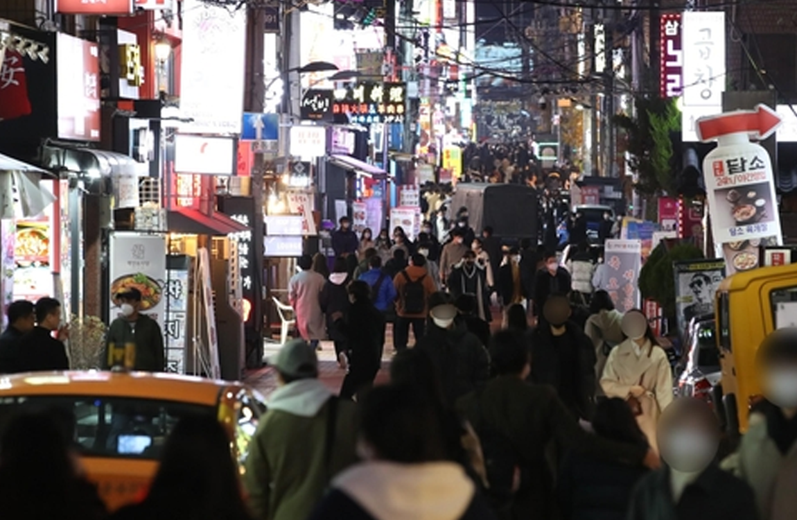 韓國街道上夜間人潮密集，眾多人佩戴口罩，顯示疫情期間民眾出行的情況。