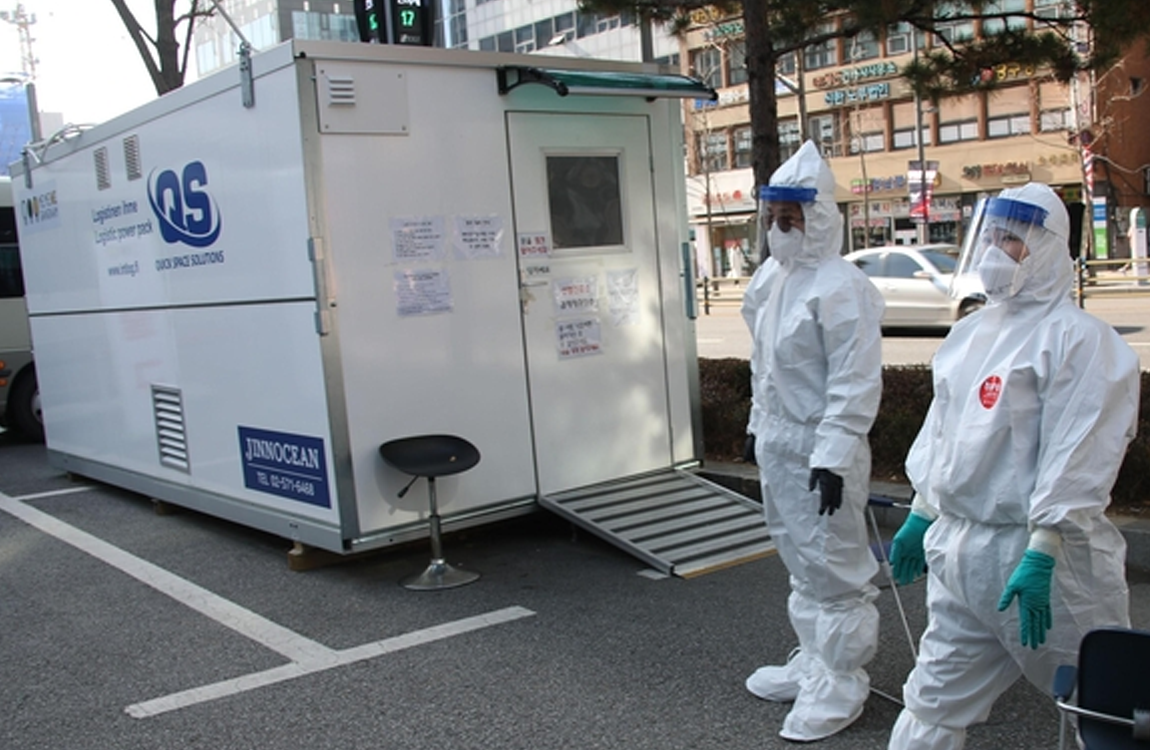 穿著防護服的醫護人員站在COVID-19快速檢測站前，作為韓國提升防疫等級的措施之一。