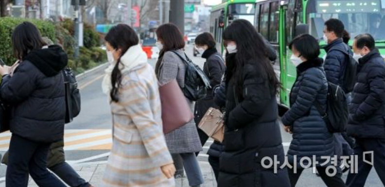 アジア経済が報じる、厳しい寒波の中で韓国で出勤する人々の様子。路面は乾いているが、寒さのため皆が厚着をしているのが見られる。
