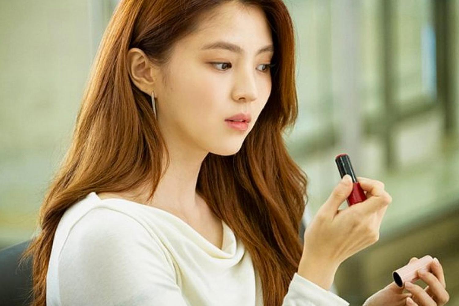 Người phụ nữ bôi son dưỡng trên môi theo chiều dọc, nhấn mạnh cách bôi đúng cách bảo vệ môi.